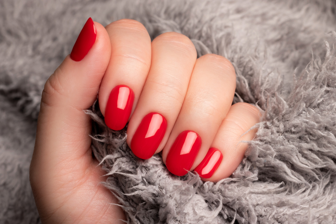 Hand with red nails on gray fluffy fabric